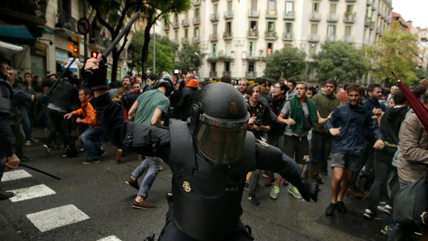 Ein spanischer Nationalpolizist schlägt in Barcelona mit einem Knüppel auf Menschen ein, die ein von der katalanischen Regierung bestimmtes Wahllokal in einer Schule erreichen wollen. Der katalanische Regierungschef Carles Puigdemont sprach von einem "ungerechtfertigten, irrationalen und unverantwortlichen" Gewalteinsatz.