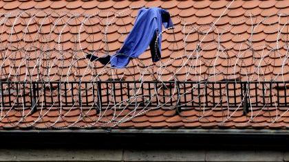 Die blaue Häftlingsjacke hängt immer noch im Stacheldraht des JVA-Dachs. Trotz Sprung in die Tiefe blieb der Flüchtende fast unverletzt. Die blaue Häftlingsjacke hängt immer noch im Stacheldraht des JVA-Dachs. Trotz Sprung in die Tiefe blieb der Flüchtende fast unverletzt.