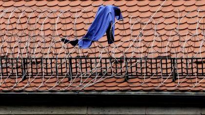 Die blaue Häftlingsjacke hängt immer noch im Stacheldraht des JVA-Dachs. Trotz Sprung in die Tiefe blieb der Flüchtende fast unverletzt.