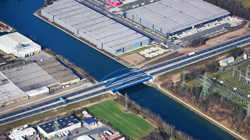 Die Brücke der A3 führt über den Kanal nach Norden. Im Hintergrund befindet sich ein großes Logistikzentrum.