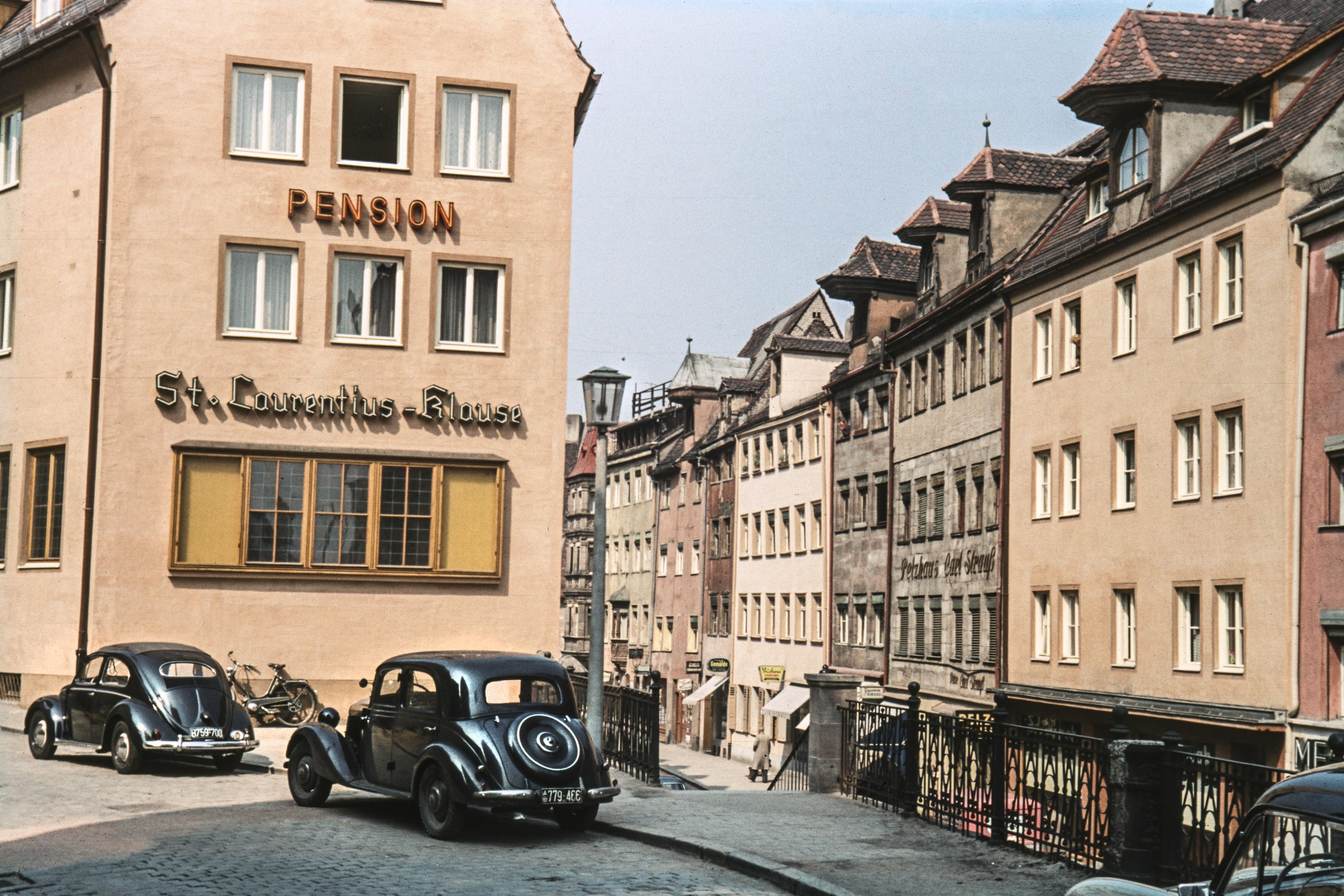 Der Mercedes im Vordergrund erweckt den Anschein, es handle sich hierbei um eine Aufnahme aus den 30er Jahren. Dieses VW-Käfer-Modell, erstmals 1953 produziert, beweist allerdings, dass das Foto aus den 50ern stammt.