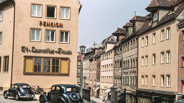 Der Mercedes im Vordergrund erweckt den Anschein, es handle sich hierbei um eine Aufnahme aus den 30er Jahren. Dieses VW-Käfer-Modell, erstmals 1953 produziert, beweist allerdings, dass das Foto aus den 50ern stammt.