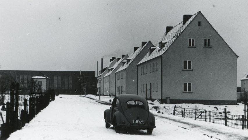 Ein einsamer VW Käfer mit Fabrik, Häuserreihe und Winterlandschaft im Jahr 1948 – aber wo?