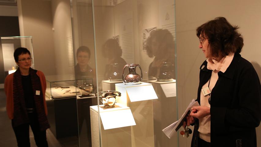 Ausstellungsmacherin Silvia Glaser (rechts) zeigt Stücke, die in den Meisterkursen entstanden sind, die Behrens in Nürnberg 1901 und 1902 abhielt.