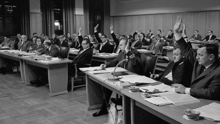 Das letzte Wort nach der Redeschlacht um Mark und Pfennig bleibt unausgesprochen: mit Handzeichen geben die Stadträte der CSU, FDP, NPD und DFU ihre Nein-Stimmen zum ordentichen Haushalt ab.  Hier geht es zum Kalenderblatt vom 7. Dezember 1967: Höhere Steuern und Gebühren im Jahr 1968