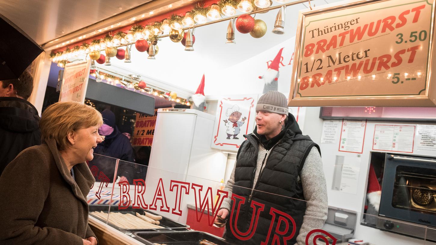 Knapp ein Jahr nach dem Terroranschlag besucht Bundeskanzlerin Angela Merkel den Weihnachtsmarkt am Breitscheidplatz in Berlin und unterhält sich mit einem Bratwurstverkäufer, sowie vielen anderen Budenbetreibern.