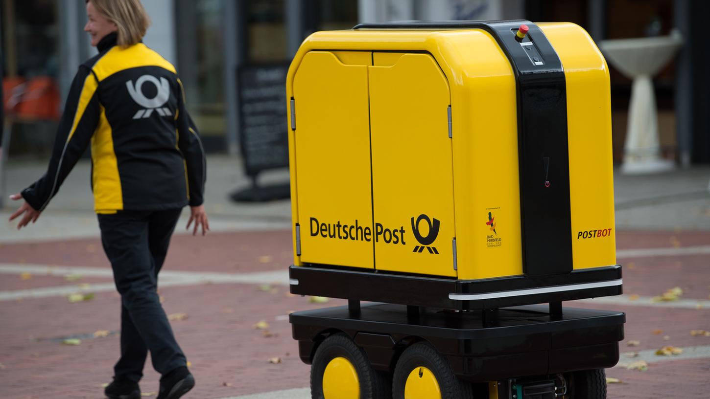 Ein Zustell-Roboter "Postbot" folgt einer Zustellerin. Die Deutsche Post hat die Testphase mit den Prototypen beendet.