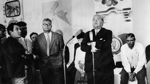 Dann eroberte die Kunst das Haus zurück. 1968 eröffnete die Künstlerbund-Ausstellung, die sich über die Kunsthalle und das Künstlerhaus erstreckte. Zur Eröffnung begrüßte Kulturreferent Hermann Glaser (mit Brille) Bundesratsminister Carlo Schmid (am Mikro) und den damals umstrittensten deutschen Künstler Joseph Beuys (sitzend). Der errichtete eine seiner berühmten Fettecken.