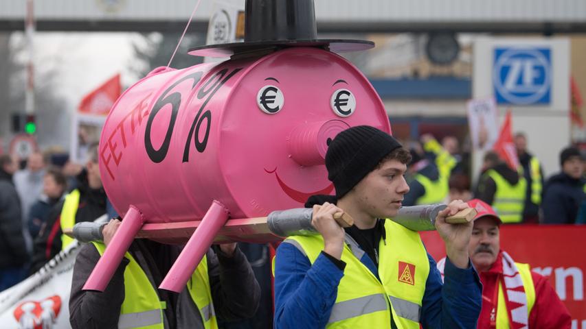 In Brandenburg an der Havel trugen die Streikenden ein nachgebautes Sparschwein  und einen überdimensionalen Wecker zum Werktor von ZF.