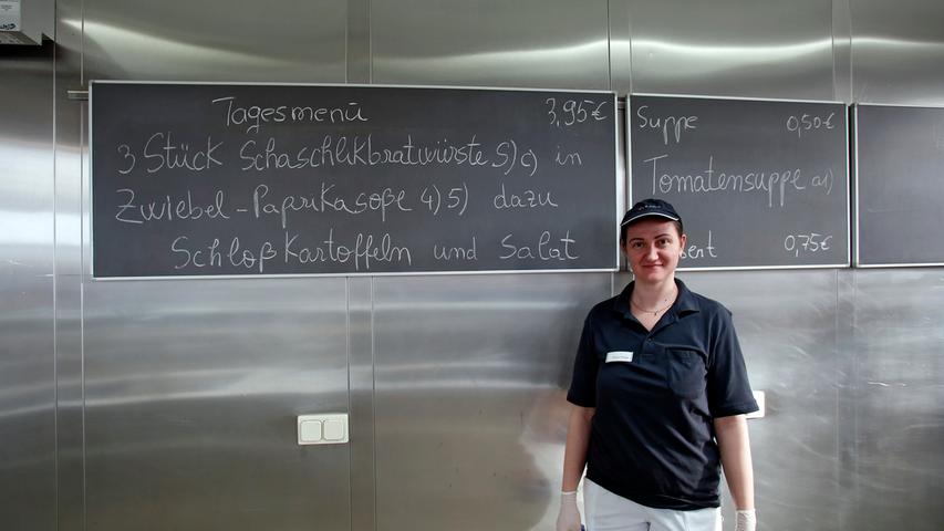 Kantinen-Mitarbeiterin Alina Oniga vor der Tafel, auf der der aktuelle Speiseplan steht.