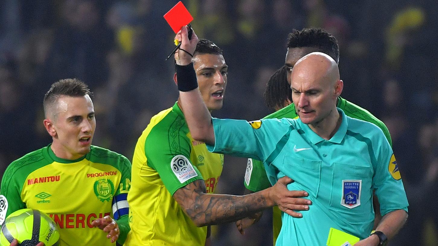 Was eine kuriose Szene: Weil er sich selbst gefoult fühlte, zeigt Schiedsrichter Tony Chapron dem für Nantes spielenden Brasilianer Diego Carlos (Mitte) Gelb-Rot.