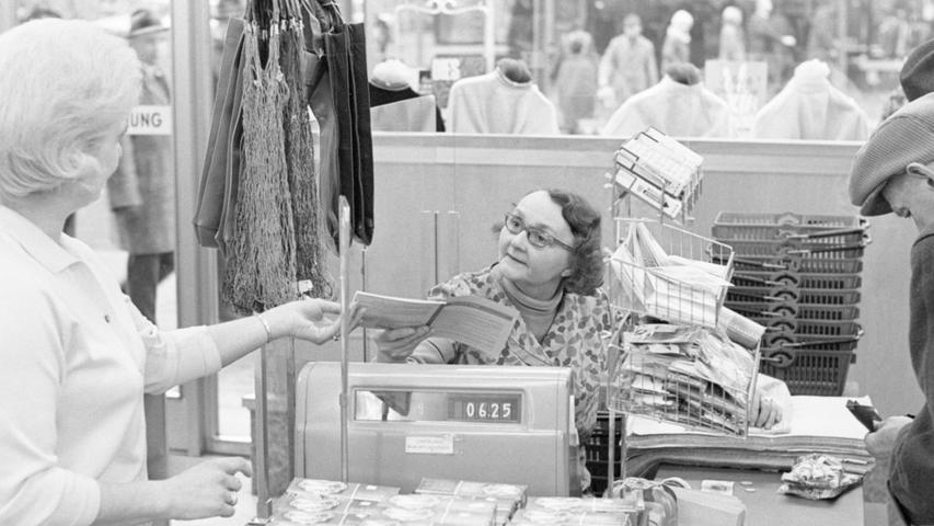 Großes Rätselraten an der Kasse im Warenhaus. Die beiden Frauen wissen nicht, ob sie die Waren gegen einen Scheck herausgeben dürfen. Hier geht es zum Kalenderblatt vom 18. Januar 1968: "Stück Preßsack für einen Scheck""