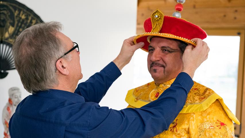 Nach dem Schminken und dem Anziehen des kaiserlichen Gewandes folgt zum krönenden Abschluss die prächtige Kopfbedeckung von Fu-gao-Di.