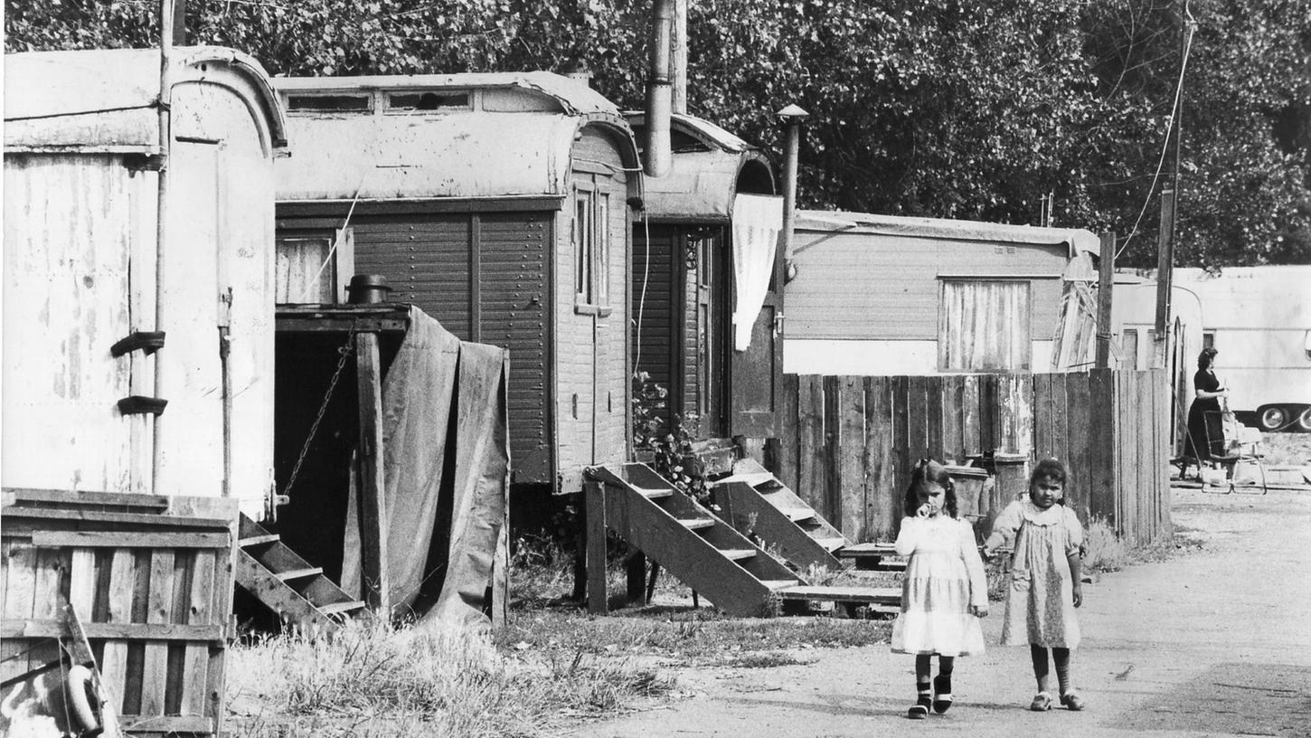 Auf diesem Bild von 1981 ist die Siedlung der Sinti und Roma auf dem Wohnwagenplatz in Gebersdorf zu sehen. Die Wohnwagen sind in schlechtem Zustand. Zwei Mädchen spazieren durch das Gebiet.