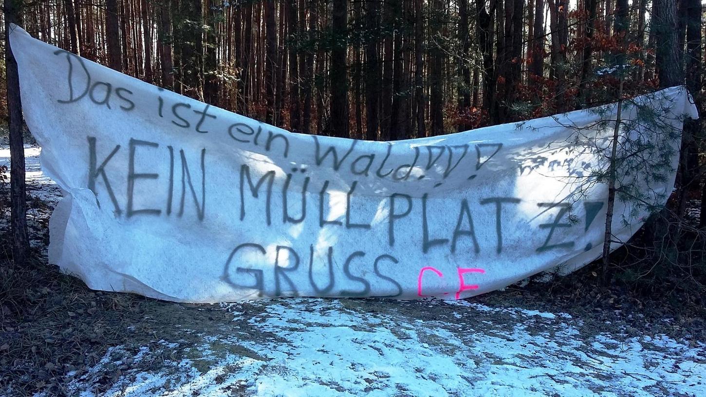 MIt einem Banner protestiert ein Eigentümer gegen die Waldverschmutzung.