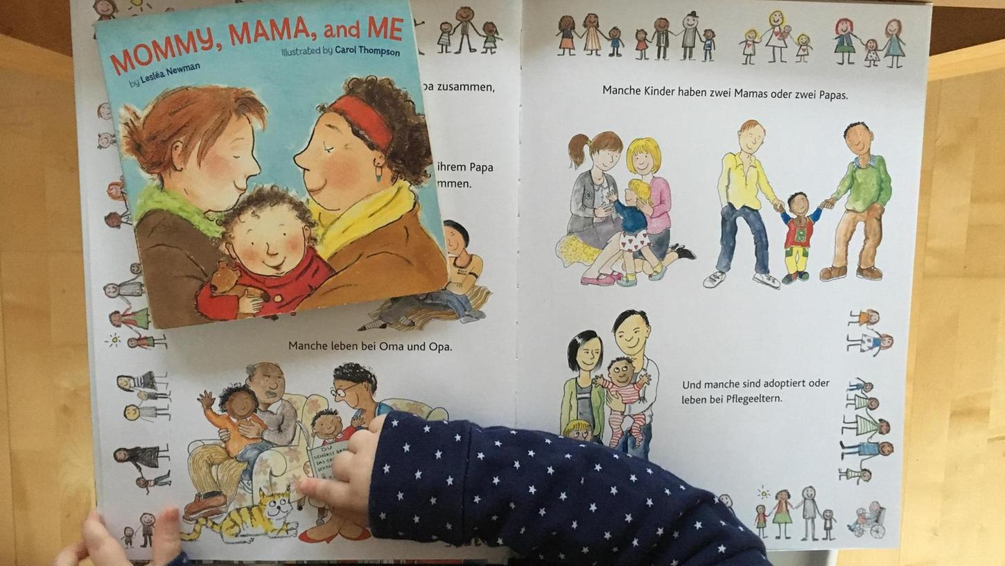 Die zweijährige Luise schaut ein Bilderbuch an: Über "Du gehörst dazu. Das große Buch der Familien", erschienen im Sauerländer-Verlag, sagen ihre Eltern, dass es die Welt zeigt, wie sie ist — bunt.