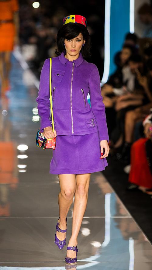 Model Bella Hadid stöckelt für Moschino im Stewardess-Outfit über den Laufsteg. Einziger Unterschied: Lila statt blau.