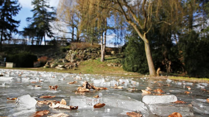 Die Wasseroberfläche vom Brunnen im Stadtpark Forchheim ist zugefroren.