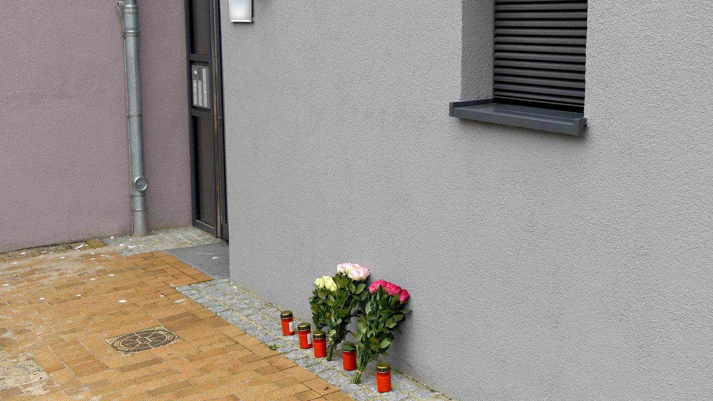 Blumen und Grablichter stehen an einem Flensburger Mehrfamilienhaus, in dem am Montag eine 17-Jährige getötet worden war. Bei dem Tatverdächtigen handelt es sich um einen abgelehnten Asylbewerber aus Afghanistan.