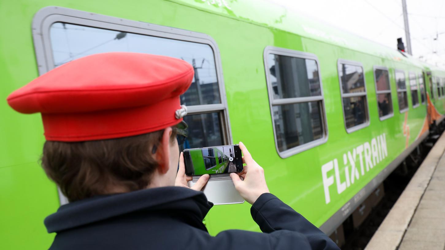 Ein Servicemitarbeiter der Deutschen Bahn filmt mit seinem Smartphone die Ausfahrt des neuen Fernzugs Flixtrain aus dem Bahnhof Köln. Bald könnten die Züge von Flixtrain auch Halt in Nürnberg machen.