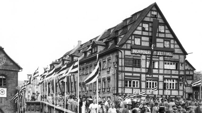 Ein Aufmarsch auf der Fleischbrücke und das NZ-Gebäude mit Hakenkreuzbeflaggung. Die Zeitung wird hier bleiben bis zur vorläufigen Einstellung im Jahr 1943.