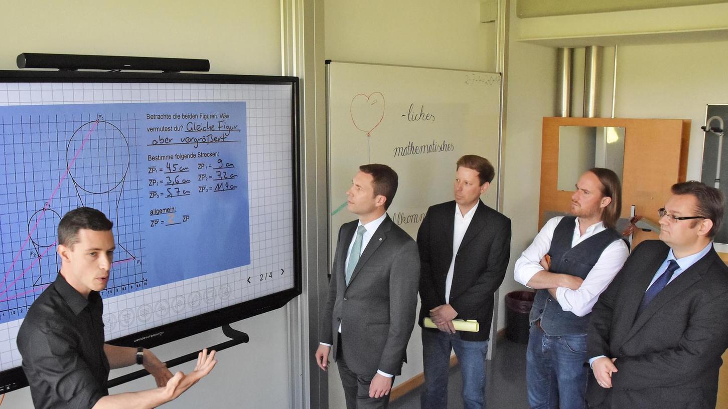 Lehrer Christoph Niemzok (links) zeigt Landrat Matthias Dießl (2. v. links) und Schulleiter Michael Gerling (rechts) die Funktion der neuen Tafeln.