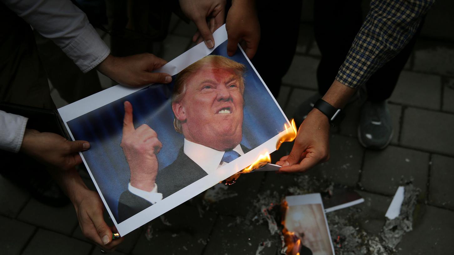 Iranische Demonstranten verbrennen ein Bild des US-amerikanischen Präsidenten Trump vor der früheren US-Botschaft. Die Proteste richten sich gegen die Sanktionen gegen den Iran.