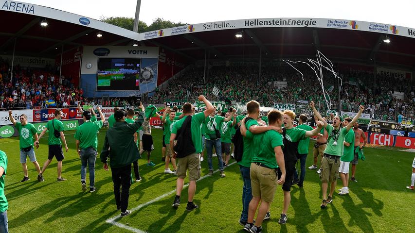 Zusammen mit den Fans feiert Fürth den Klassenerhalt. Die Anhänger in weiß-grün haben den Platz eingenommen, verhalten sich friedlich und sind erleichtert, nächste Saison weiter in Liga zwei zu sein.