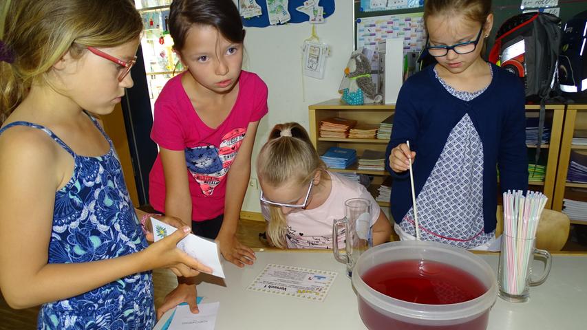 Diese jungen Forscherinnen zeigten, wie Luft und Wasser zusammenpassen, indem man ein Glas kopfüber ins Wasser stürzt und dadurch eine kleine Luftblase entsteht.