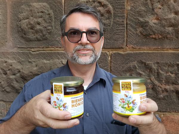 Karsten Burghardt, Vorsitzender des Zeidlervereins Nürnberg und Umgegend, hält zwei Honiggläser aus der eigenen Imkerei in Händen.