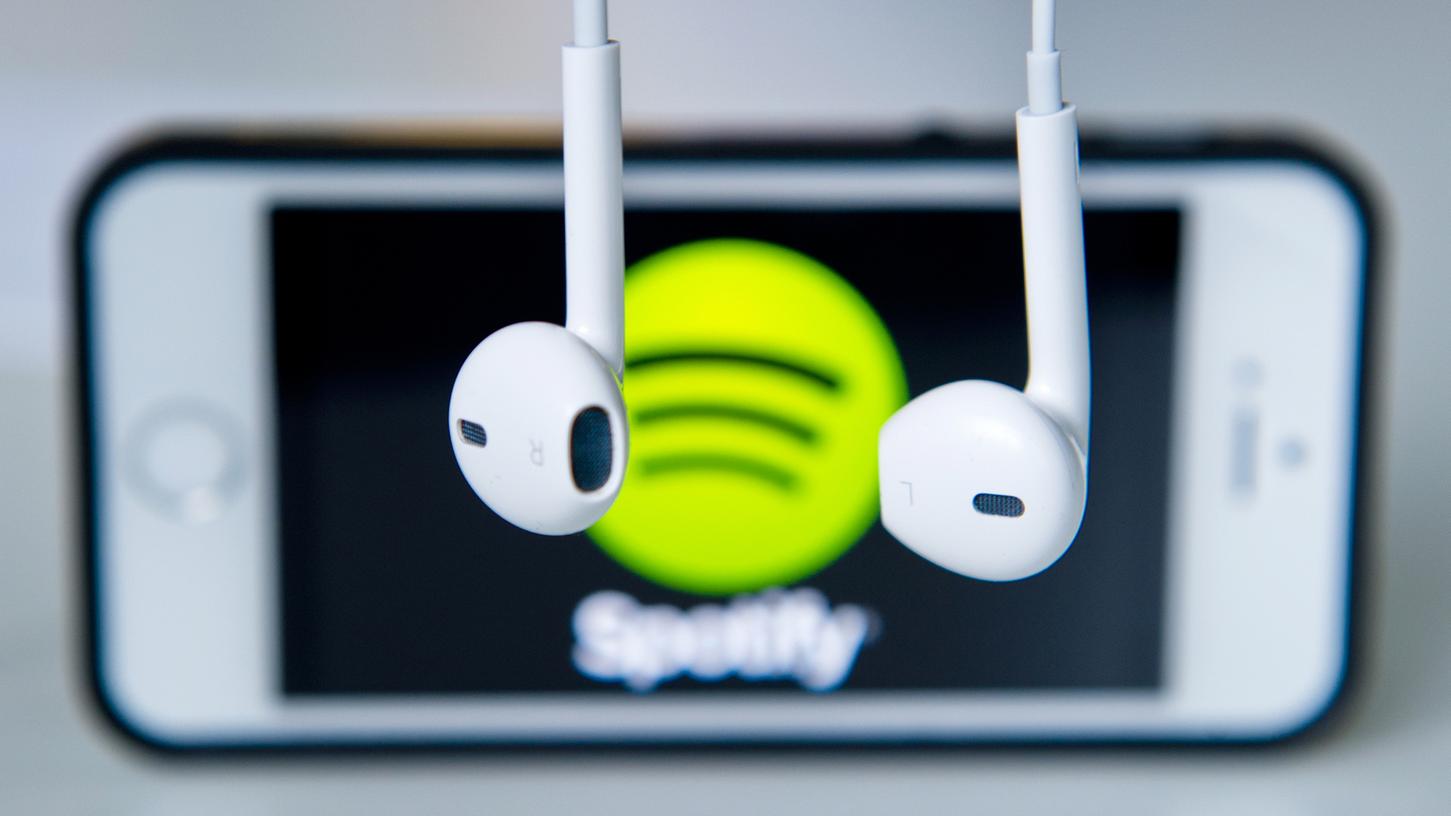 Kopfhörer hängen vor einem Apple IPhone 5s, auf dem das Logo vom Musik-Streaming-Dienst Spotify angezeigt wird. Der deutsche Musikmarkt hat ein erneutes Wachstum verzeichnet.