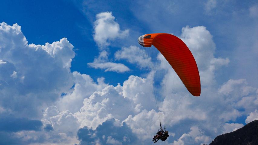 Ein Paraglider segelt im Tandem vom Piffinger Köpfl ins Tal.