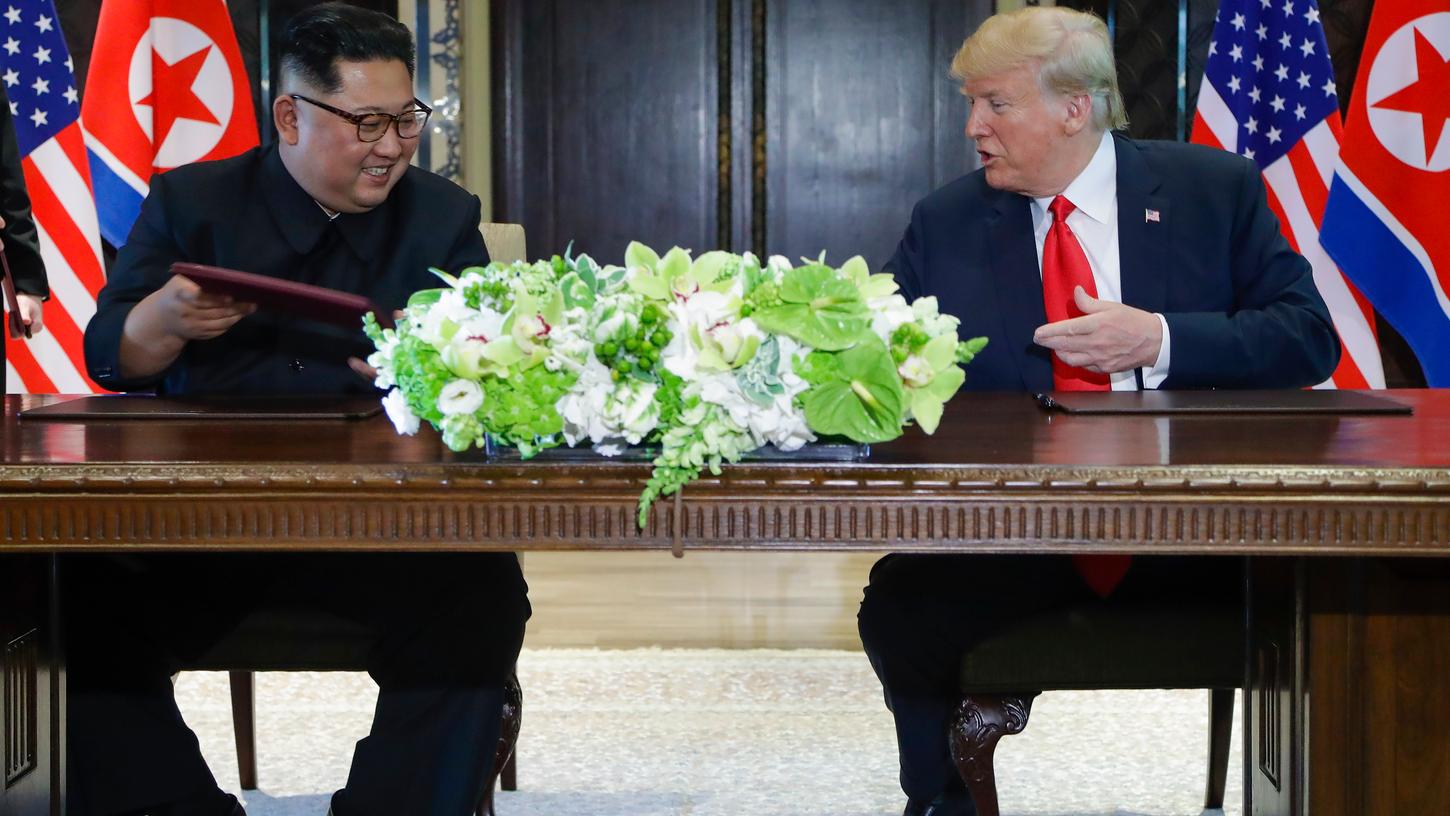 U.S. Präsident Donald Trump (r) und der Machthaber von Nordkorea Kim Jong Un tauschen die Dokumente nach der Unterzeichnung einer gemeinsame Vereinbarung.
