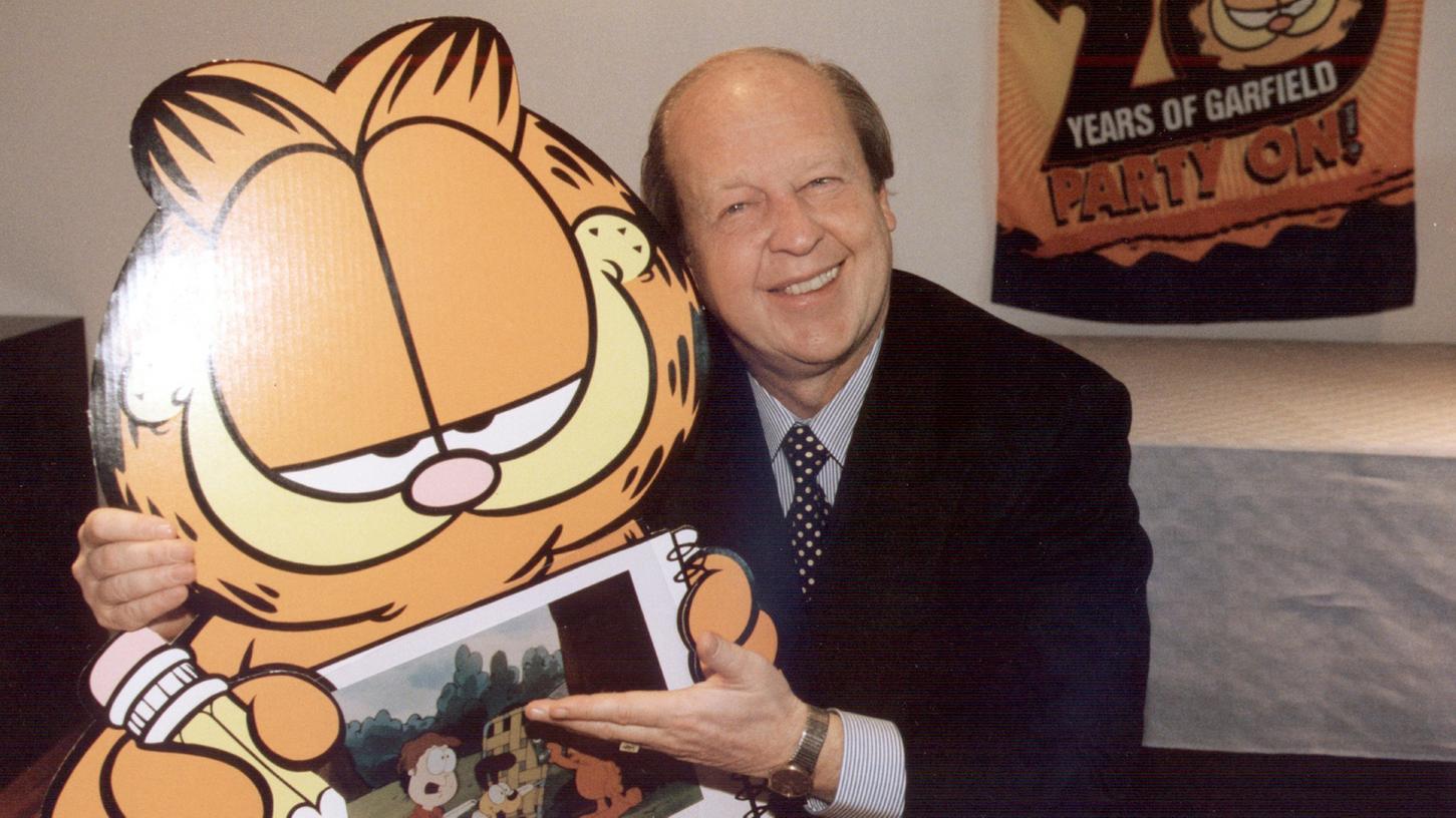 Der US-amerikanische Comiczeichner Jim Davis posiert mit einem Pappaufsteller seiner Comic-Katze Garfield. Weil er in seiner Kindheit mit zahlreichen Katzen aufwuchs, schuf er vor 40 Jahren den dicken Zeichentrick-Kater.