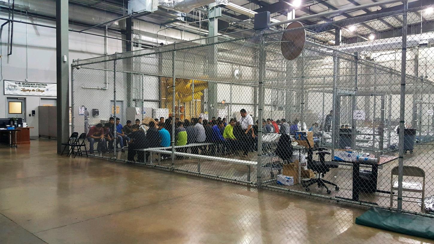 Die von der US-Grenzschutzbehörde zur Verfügung gestellte Aufnahme zeigt Menschen, die im Zusammenhang mit illegalen Grenzübertritten in die USA in Gewahrsam genommen wurden und in einem Käfig sitzen.