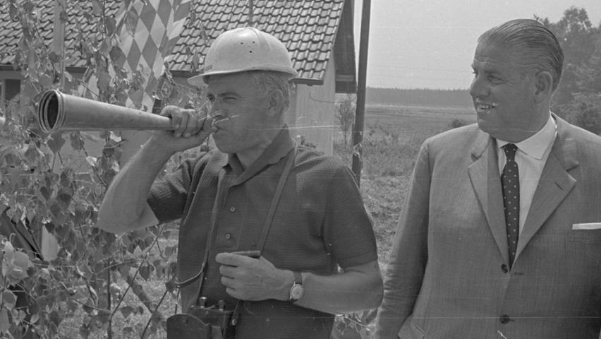 Das Signal zum Beginn der Arbeiten am Hafen ertönt: Sprengingenieur Hans Dreier (rechts) stößt ins Horn, um die Arbeiter im Gelände zu warnen.Hier geht es zum Kalenderblatt vom 6. Juli 1968: Erster Schritt zur Hafenstadt"