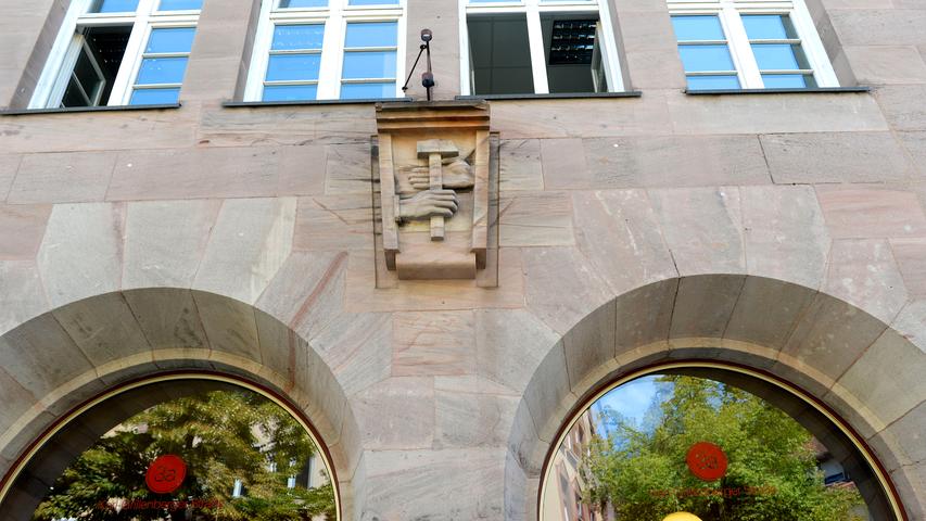 Wie ein Wappen prangt das Motiv der Hände, die einen Hammer umfassen, über dem Haupteingang des oberen Gebäudeteils.