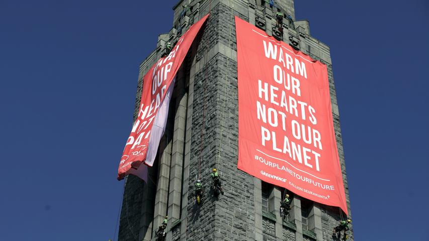 Währenddessen wird draußen demonstriert: Die Umweltschutzorganisation Greenpeace protestiert mit Bannern "Warm our hearts not our planet (Wärmt unsere Herzen, nicht unseren Planeten) in Helsinki gegen den Gipfel.
