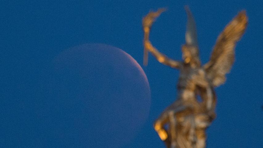Der aufgehende Mond ist hinter einer vergoldeten Engelsfigur auf dem Dach der Hochschule für bildende Künste zu sehen. Bei der längsten Mondfinsternis des 21. Jahrhunderts taucht der Mond in den Erdschatten ein.