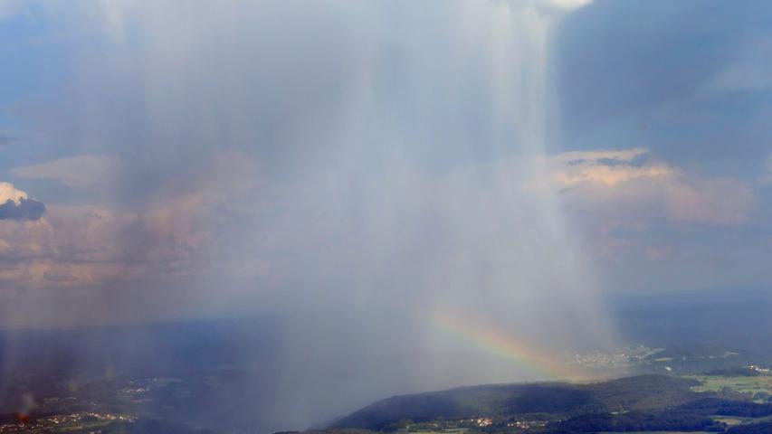 Hier zu sehen ist eine Regenfront und ein Regenbogen über der Fränkischen Schweiz - und zwar sicher aus dem trockenen Flugzeug aus. Für die Menschen unten auf der Erde war der Anblick wohl ein wenig unerfreulicher als für unseren Fotografen.