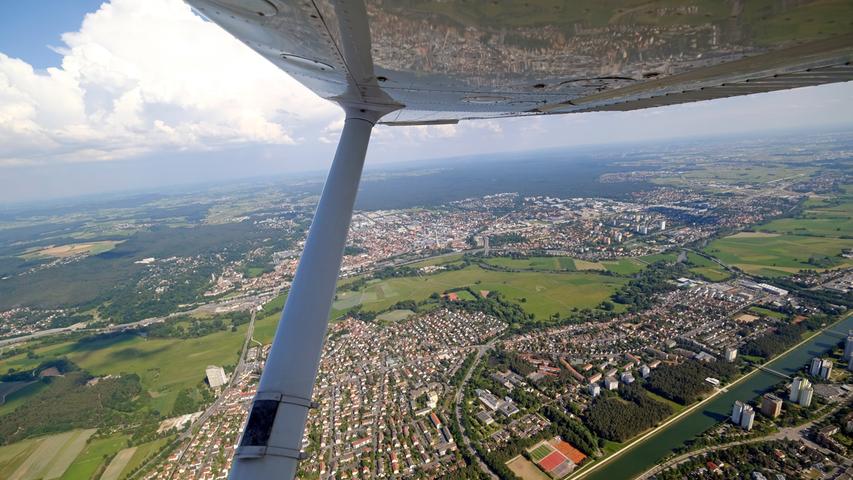 Erlangen zeigt sich aus dem Flugzeug in verschiedenen Facetten: Einmal wie eine Spielzeugstadt unten auf dem Erdboden, aber auch als kecke Spiegelung im Flügel.