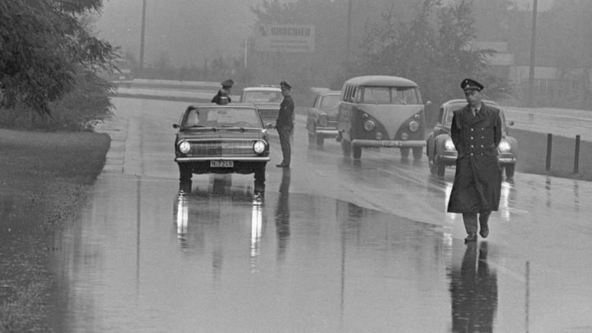 Engpaß in der Münchener Straße: wegen der breiten Wasserpfütze blieb nur eine Fahrspur frei. Bis das Hindernis beseitigt war, stellte die Polizei zur Sicherung Posten auf. Hier geht es zum Kalenderblatt vom 9. August 1968: Ärger mit dem Regen
