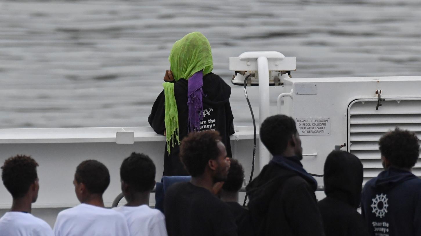 Migranten stehen an Deck des italienischen Küstenwachschiffs "Diciotti", das nach mehreren Tagen im Mittelmeer in den Hafen von Catania eingelaufen ist. Die 177 Migranten an Bord dürfen das Schiff allerdings zunächst nicht verlassen.