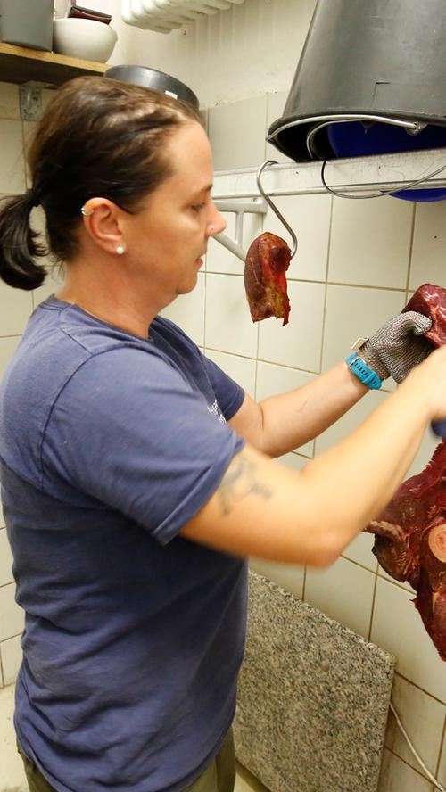 Raubkatzenpflegerin Alexandra Hoffmann schneidet Subali ein großes Stück Rindfleisch ab.