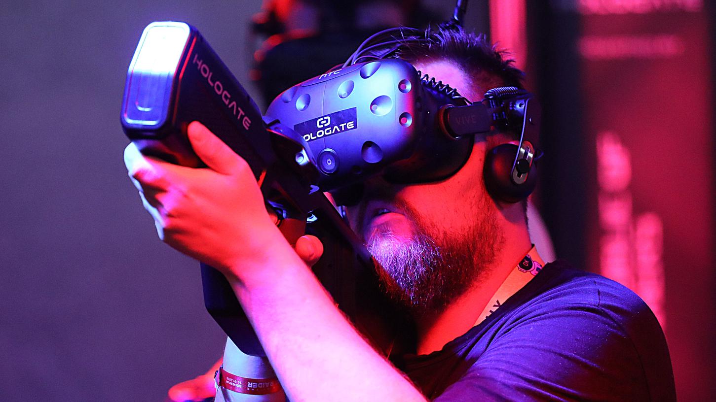 Besucher der Gamescom in Köln spielen mit VR-Brillen auf dem Stand von Hologate.