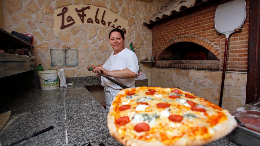 Ein Herzstück des Lokals ist der Holzbackofen: Marina Lenzi holt eine frisch gebackene Pizza aus der Glut.