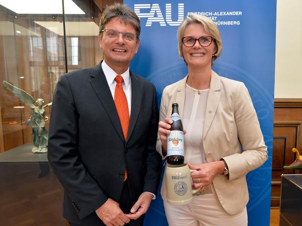 Anja Karliczek bekommt von Unipräsident Joachim Hornegger das Uni-Jubiläums-Bier "Helles Köpfchen" überreicht.