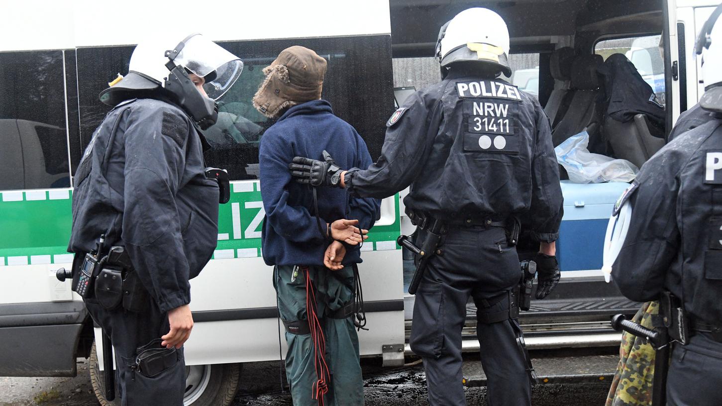 Polizisten bringen bei der Räumungsaktion im Hambacher Forst einen Aktivisten zu einem Einsatzwagen.