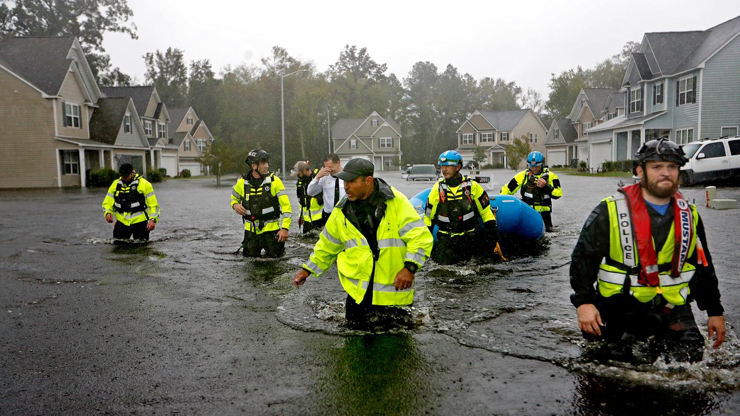 Mitglieder eines Rettungsteams wateten durch ein überschwemmtes Viertel auf der Suche nach Bewohnern, die in ihren Häusern zurückblieben.