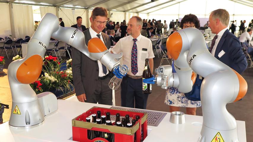 Mit der Einweihung ihres neuen Verwaltungsgebäudes am Hauptsitz in der Treuchtlinger Industriestraße bekannte sich die Firma Alfmeier nicht nur zu ihrem ländlichen Standort, sondern richtete den Blick mit ihrem „Technology Day“ zugleich weit darüber hinaus auf die gesamte Welt sowie den Wandel von Arbeit, Konsum und Gesellschaft im Zeitalter der Digitalisierung. Einen Einblick in die Arbeitsweise im Werk und den Labors gaben zwischen Festakt und Podiumsdiskussion zum Thema „Digitalisierung und die Auswirkungen auf die Arbeitswelt“ mehrere Rundgänge durch das Unternehmen. Dabei gab es auch schon einen Vorgeschmack auf die gerade entstehende „Smart Factory“ in Kooperation mit Siemens. Eine technische Spielerei, die zeigt was möglich ist, waren zwei Roboterarme, die Weißbier einschenkten. Für einen Schreckmoment sorgte das heftige Gewitter, das am späten Nachmittag kurzzeitig drohte, das Festzelt wegzublasen und unter Wasser zu setzen. Mit der Einweihung ihres neuen Verwaltungsgebäudes am Hauptsitz in der Treuchtlinger Industriestraße bekannte sich die Firma Alfmeier nicht nur zu ihrem ländlichen Standort, sondern richtete den Blick mit ihrem „Technology Day“ zugleich weit darüber hinaus auf die gesamte Welt sowie den Wandel von Arbeit, Konsum und Gesellschaft im Zeitalter der Digitalisierung. Einen Einblick in die Arbeitsweise im Werk und den Labors gaben zwischen Festakt und Podiumsdiskussion zum Thema „Digitalisierung und die Auswirkungen auf die Arbeitswelt“ mehrere Rundgänge durch das Unternehmen. Dabei gab es auch schon einen Vorgeschmack auf die gerade entstehende „Smart Factory“ in Kooperation mit Siemens. Eine technische Spielerei, die zeigt was möglich ist, waren zwei Roboterarme, die Weißbier einschenkten. Für einen Schreckmoment sorgte das heftige Gewitter, das am späten Nachmittag kurzzeitig drohte, das Festzelt wegzublasen und unter Wasser zu setzen.